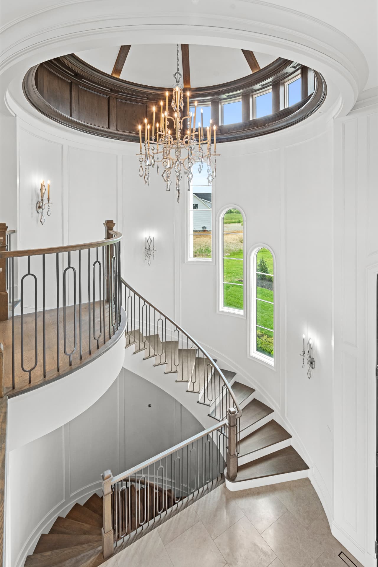 Curved architectural staircase beneath a crystal chandelier