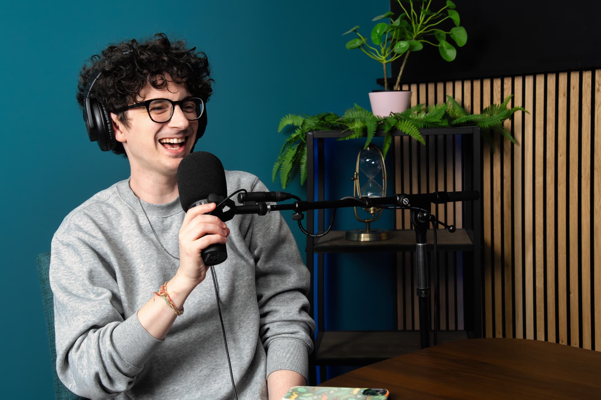 Guest laughing behind a broadcast microphone during a studio recording