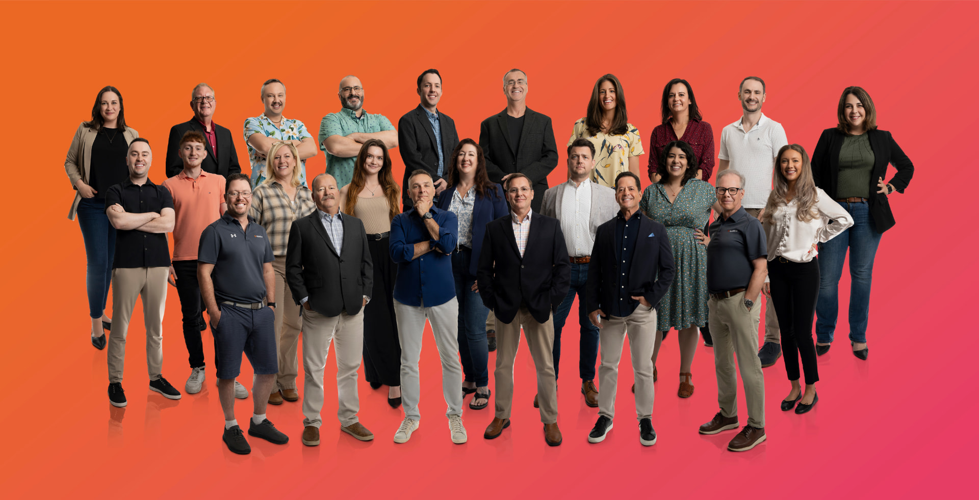 Full company team composite portrait against a bold orange studio backdrop